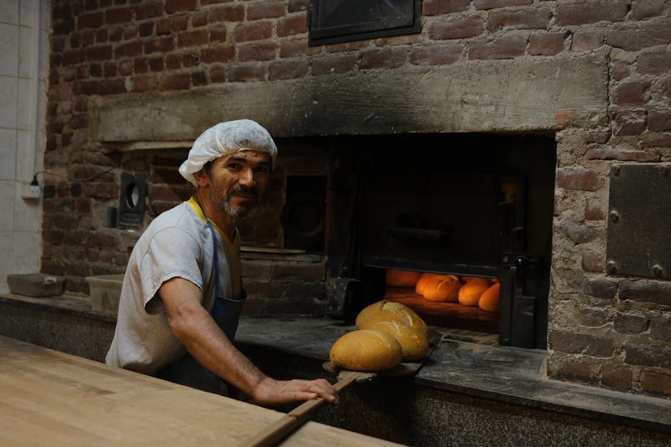 A skilled baker handling freshly baked bread in a traditional brick oven bakery.