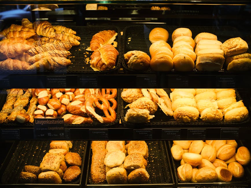 A diverse array of freshly baked bread, rolls, and pastries inside a bakery display case.